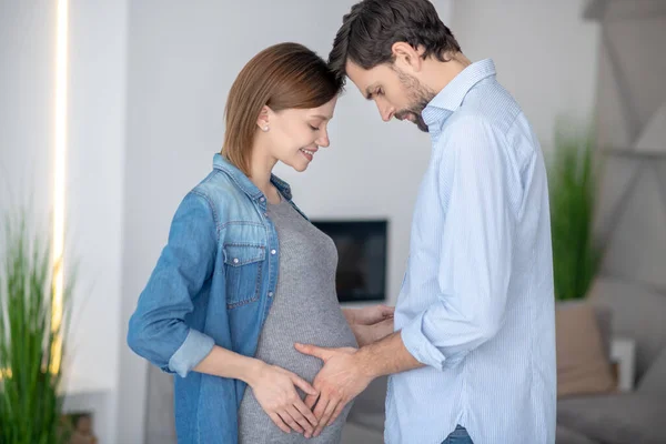 Ung mörkhårig man vidrör sin fru gravid buk — Stockfoto