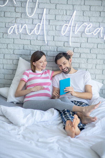 Pregnant woman and her husband surfing internet and feeling relaxed