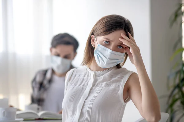 Junge Frau mit Gesichtsmaske hat Kopfschmerzen — Stockfoto