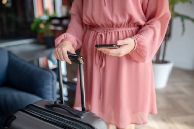 Cep telefonu ve bavul sapını tutan kadınların yakın çekimleri