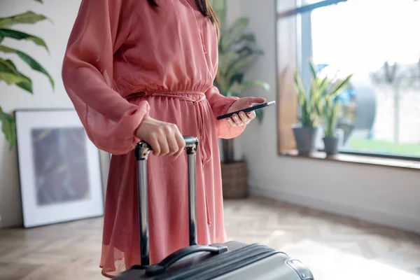 휴대 전화와 여행 가방 손잡이를 들고 있는 여성 손의 근접 사진 — 스톡 사진