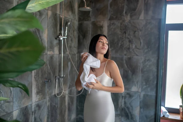 夜のドレスでシャワーに立つブルネットの女性、タオルで拭く — ストック写真