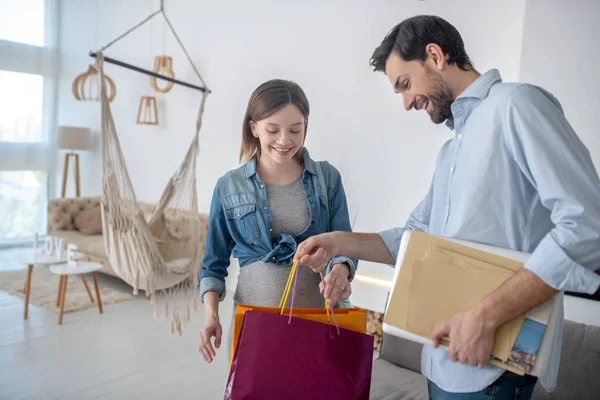 Hombre moreno sosteniendo bolsas de compras y sonriendo — Foto de Stock