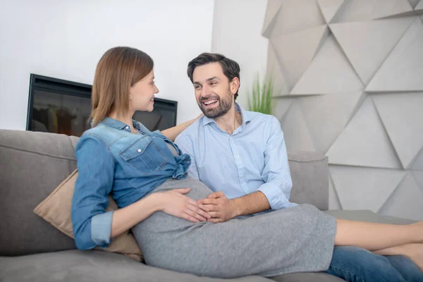 Young pregnant woman in a jeans jacket feeling amazing with her husband at home — Stock Photo, Image