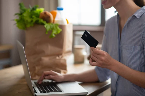 Girl in grey homewear holding a credit card and paying online — Stock Photo, Image