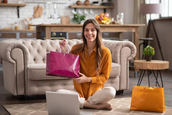 Chica de pelo largo en una blusa de color mostaza sosteniendo una bolsa de compras y sonriendo — Foto de Stock