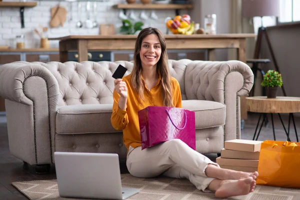 Chica de pelo largo en una blusa de color mostaza sosteniendo una bolsa de compras y una tarjeta de crédito — Foto de Stock