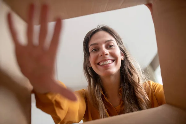 Smiling young girl opening the box and stretching her hand — Stock Photo, Image