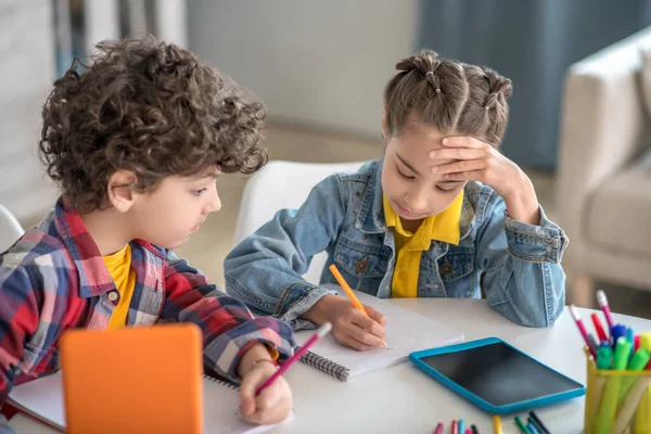 Jongen en meisje zitten aan een ronde tafel met tabletten en bereiden hun opdrachten voor — Stockfoto