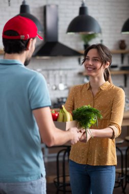 Koyu saçlı bayan müşteri kuryeden yiyecek alıyor ve kendini iyi hissediyor.