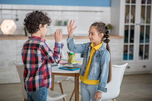 Chica de pelo oscuro y niño rizado sonriendo, dando choco cinco el uno al otro — Foto de Stock