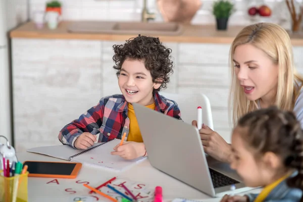 Lockiger Junge und dunkelhaariges Mädchen sitzen am Tisch, erledigen ihre Aufgaben, diskutieren etwas — Stockfoto