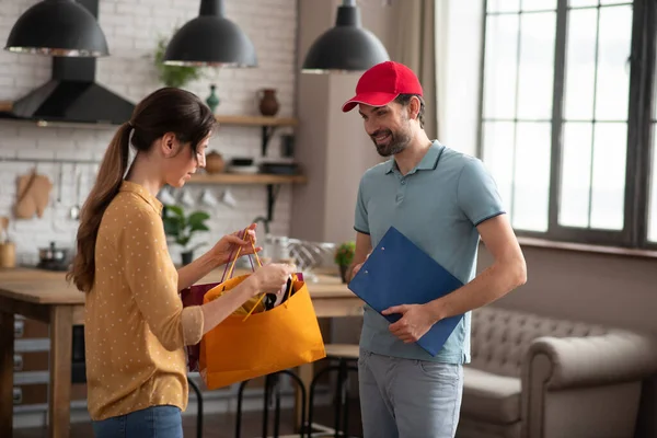 Donkerharige klant opent de boodschappentas geleverd door de courrier — Stockfoto