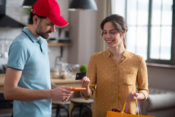 Cliente femenino dando una tarjeta de crédito a la persona de entrega para el pago y sonriendo — Foto de Stock