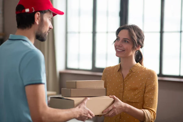 Cliente femenino recibiendo cajas de una persona de entrega y buscando satisfecho — Foto de Stock