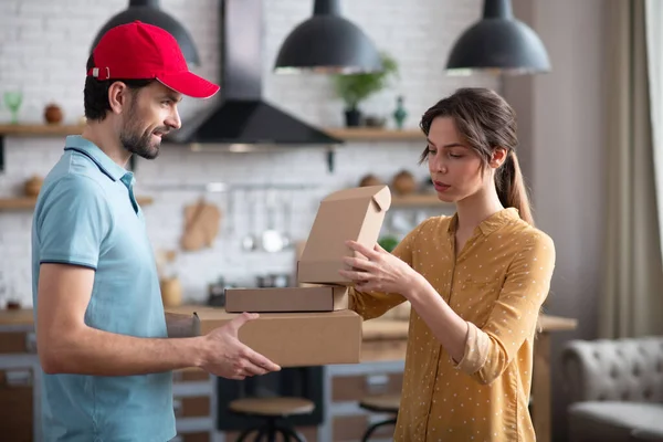 Женщина-клиент получает коробки от доставщика и выглядит сосредоточенной — стоковое фото