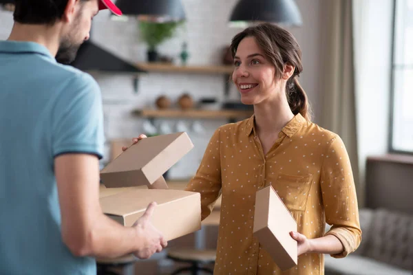 Cliente femenino recibiendo cajas de una persona de entrega y buscando satisfecho — Foto de Stock