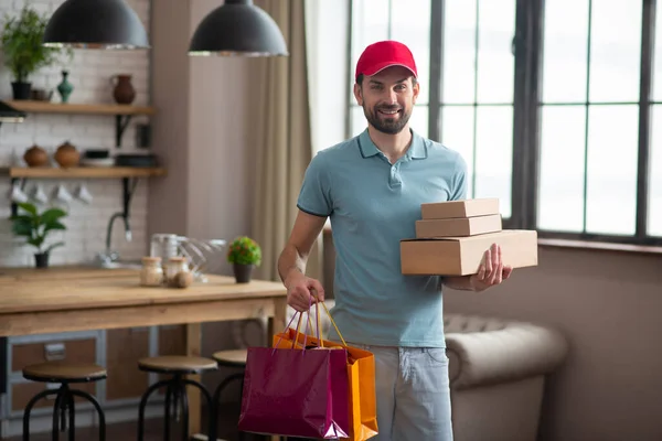 Entrega persona en un sombrero rojo sosteniendo las cajas — Foto de Stock