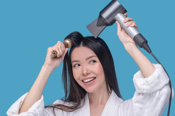 Morena joven asiática mujer secándose el pelo y sonriendo — Foto de Stock