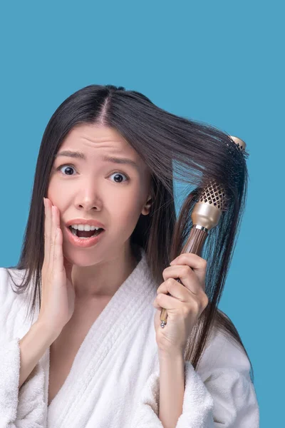 Dunkelhaarige asiatische Frau bürstet sich die Haare und fühlt sich gestresst — Stockfoto