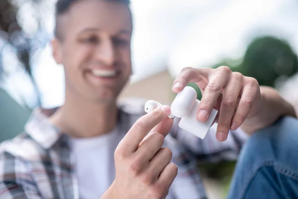 Scatola di contenimento maschio dai capelli scuri sorridente con auricolari wireless — Foto Stock