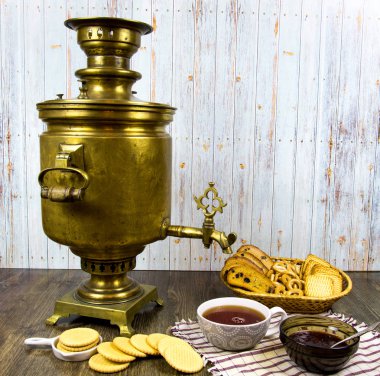 Ahşap bir masanın üzerinde antika bakır semaver ve bir fincan çay kırıntısı reçeli. Halkın gelenekleri, kültürü, mutfağı.