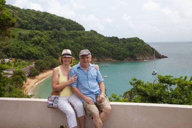 Güneşli bir günde, taştan bir korkulukta oturan mutlu bir çift güzel Karayip Körfezi 'nin, Tobago adasının zeminine karşı. Dünya turizmi, eğlence, cennet..