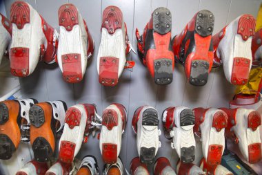 Ski boots of various colors installed in a row with the soles up in the rental of ski equipment. Sports, recreation, Hobbies.