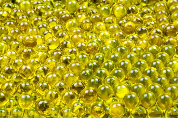 Keten tohumu yağı kapsülleri kontrastlı ışıkta parlak sarıdır, yumurtalara benzer. Arkaplan dokusu tasarımı.