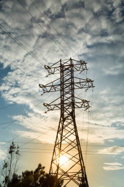 Bulutların ve batan güneşin arkaplanındaki elektrik hattının görüntüsü. Emlak, mühendislik. 