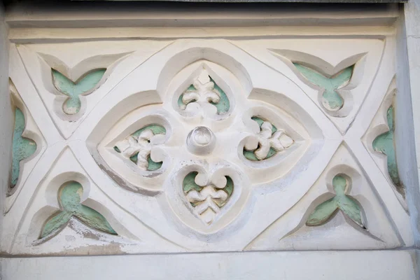 The element of finishing of a facade plaster. Rectangle inside four flowers at the edges of the petals are white some elements are turquoise. Architecture design details construction.