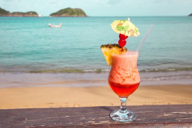 Arka planda şemsiyesi olan kırmızı kokteyl anananaslı bir bardak Turkuaz Deniz Turizmi Dünya Turizmi