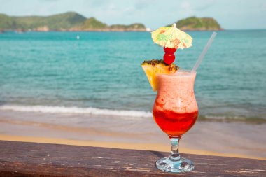 Arka planda şemsiyesi olan kırmızı kokteyl anananaslı bir bardak Turkuaz Deniz Turizmi Dünya Turizmi