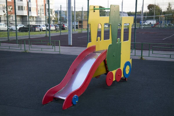 住宅団地の庭に電車の形で木製のスライド明るい赤青緑 遊び場 おもちゃ — ストック写真