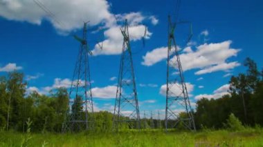 Güzel gökyüzünün altında elektrik hatları olan beyaz bulutların zaman akışı. Enerji tasarrufu kavramı. Mavi gökyüzünde elektrik direkleri ve çizgiler. Enerji korunumu. döngülenebilir 