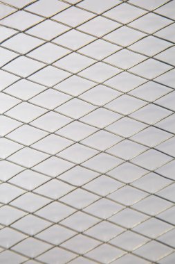 Beyaz zemin, arka plan, doku ve dizayn üzerinde elmas şekilli hücreleri olan metal örgüler..