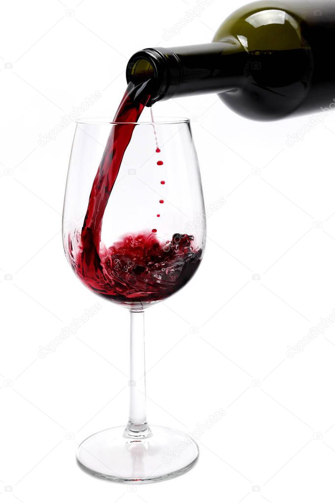 Red wine poured from a bottle in a elegant crystal goblet, isola
