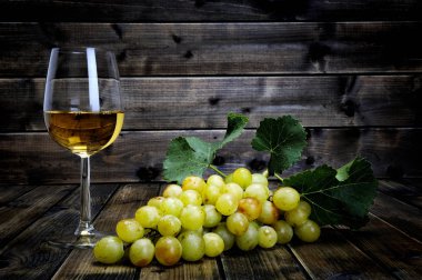 Şarap kadehi ve taze beyaz üzüm antika ahşap bac üzerinde demet