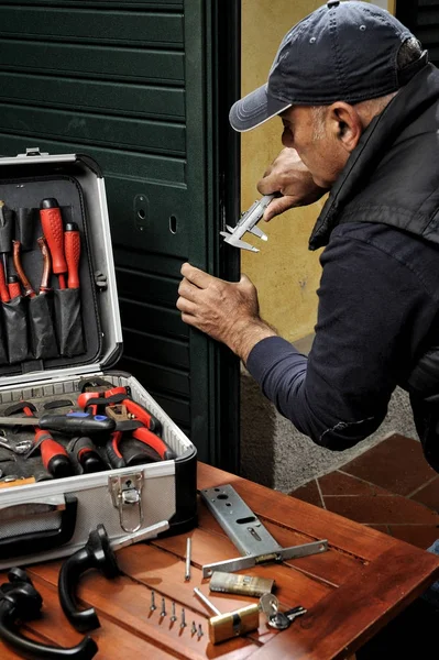 Carpinteiro que trabalha a substituição da fechadura de uma porta . — Fotografia de Stock