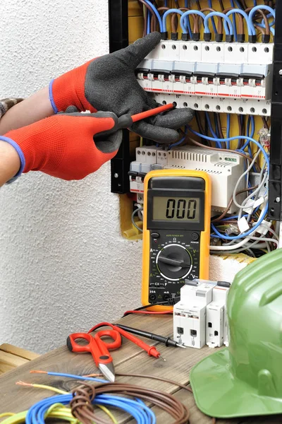 Técnico electricista joven en el trabajo en un panel eléctrico con — Foto de Stock