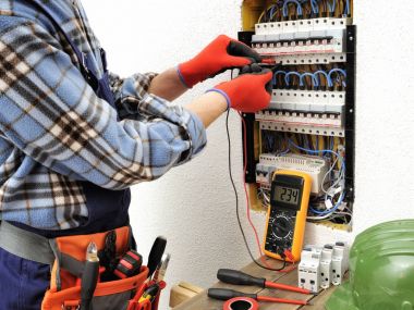 Bir elektrik panel ile iş yerinde genç Elektrikçi Teknisyen 