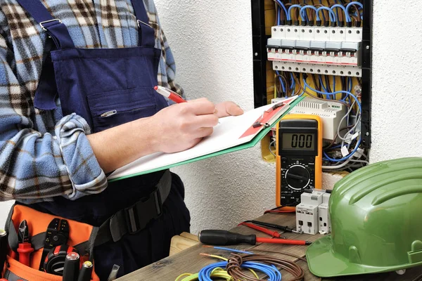 Jovem eletricista técnico no trabalho em um painel elétrico — Fotografia de Stock