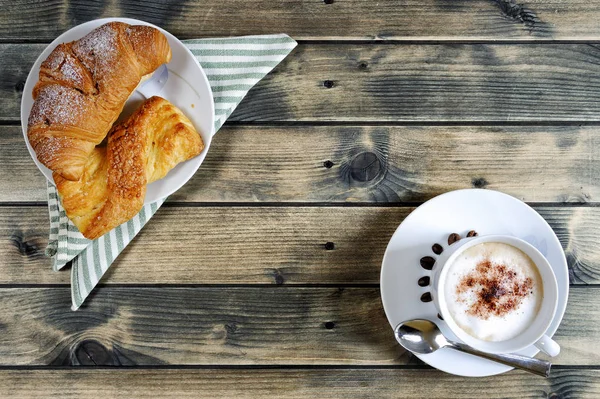 Traditional Italian breakfast with cappuccino and croissants on a rustic wooden table — Stock Photo, Image