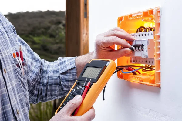 Técnico eletricista repara o painel elétrico de um sistema residencial — Fotografia de Stock