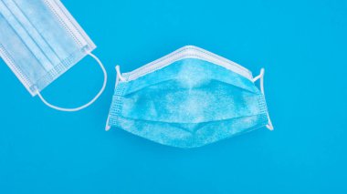 Coronavirus önleme. Açık mavi arka plandaki Covid-19 enfeksiyonunu önlemek için tıbbi ya da cerrahi maske. Yukarıdan görüntüle.