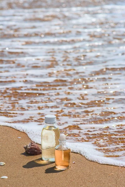 Botellas con esencia de aceite y concha en las olas del mar. Spa y wel — Foto de Stock