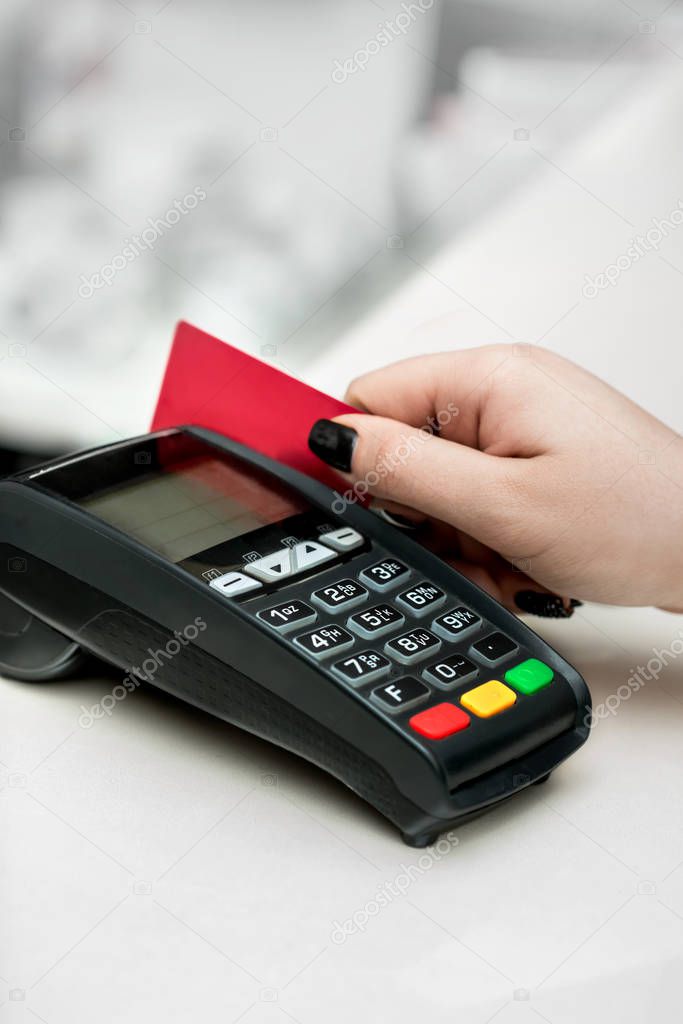 Woman hand using payment terminal in  shop. Paying with credit o