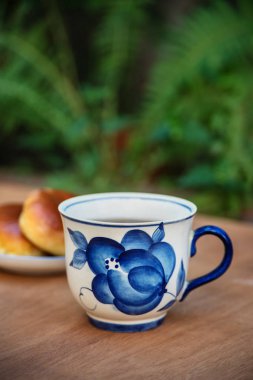 Çay takımı. Porselen bardak ve çaydanlık, açık havada kekler.. 