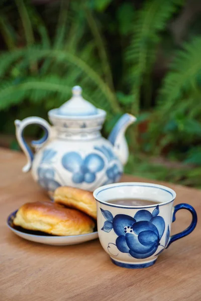 Çay takımı. Porselen bardak ve çaydanlık, açık havada kekler.. 