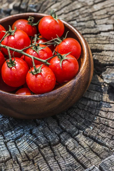 Tomates cerises dans une assiette sur une vieille surface en bois, espace pour le texte . — Photo